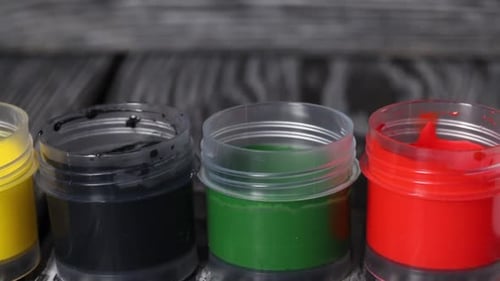 Un ensemble de gouache. Ouvrez des pots de peinture. Sur des planches de pin. Caméra Slider. Gros plan..