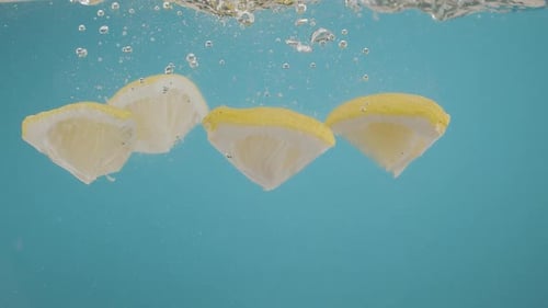 Lemon Slices Dropping into Water with Bubbles