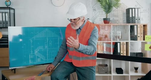 Arquitecto con casco y chaleco explicando la presentación en pantalla digital y aplaudiendo