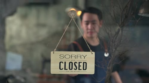 4K Asian man coffee shop owner turning hanging closed sign to open on the door