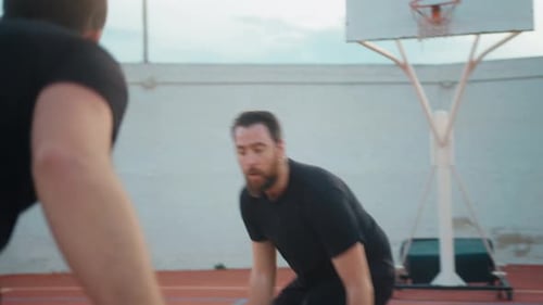 Close up of male friends playing basketball on court outdoors during sunny day