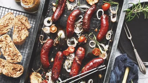 Top View on Delicious Grilled Sausages Served with Onion Tomatoes Garlic Bread and Herbs