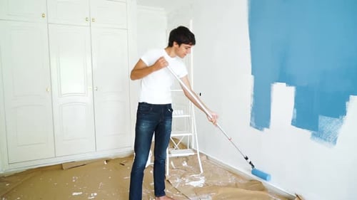 junger Mann malt Wand in blauer Farbe