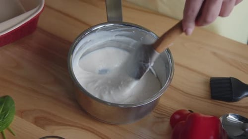 Person Mixing White Sauce in Pot With Spatula