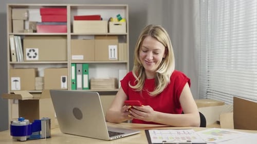 Warehouse Worker is Working in an Office Room Against Background of Boxes