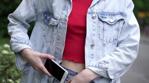 Young Woman Puts Phone in Jeans Pocket