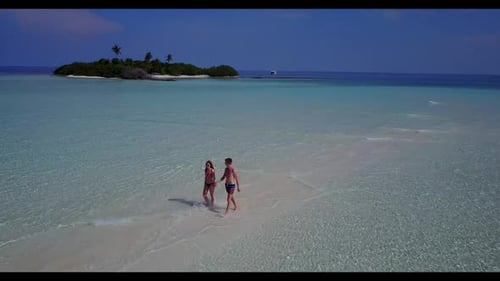 Two lovers suntan on marine island beach break by shallow lagoon with clean sand background of the M