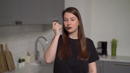 Smiling Woman with Spoon Standing in Kitchen