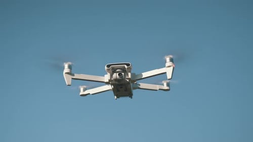White Drone Flying on Nature Background. Drone Hanging in Air Flying Helicopter Dron Remote Control
