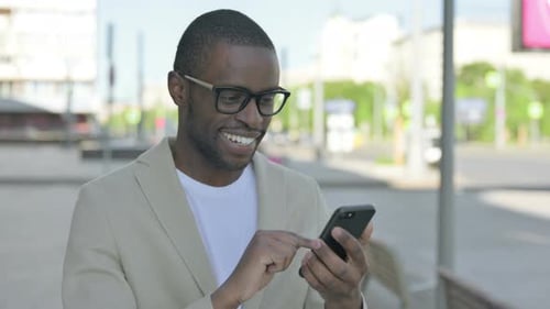 Young Adult Using Mobile Phone on City Street