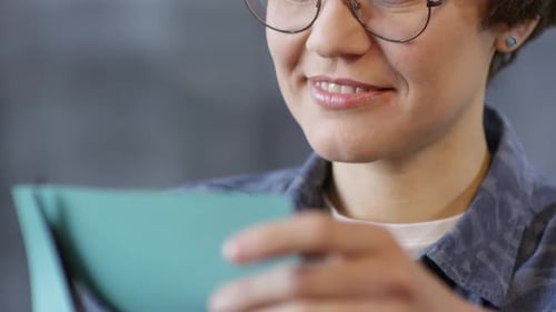 Adult with Glasses Cutting Paper with Scissors