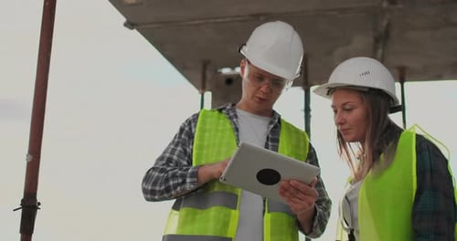 Baustellenteam oder Architekt und Baumeister oder Arbeiter mit Helmen diskutieren auf einem Gerüst