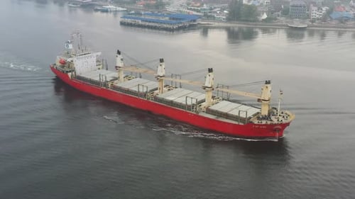 Drone flyover and around international cargo ship, empty barge with no shipments, sailing on the sea