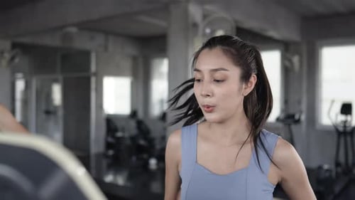 4K Portrait of Asian sportswoman in sportswear jogging workout exercise on treadmill at fitness gym.