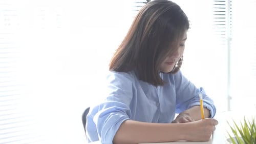 Young Woman Writing and Typing at Modern Desk