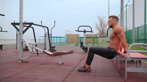 Shirtless Man Working out Outdoors with Tricep Dips