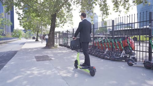 Jeune homme d'affaires conduisant un scooter électrique à l'extérieur