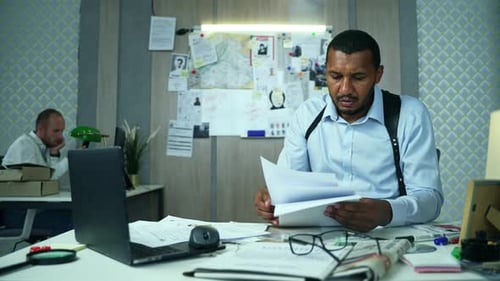 Serious Detective Examining Case Documents in Office