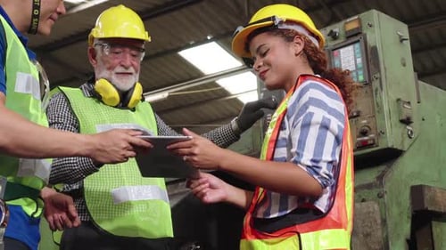 Gruppe von Fabrikarbeitern, die Maschinenausrüstung in der Fabrikwerkstatt verwenden
