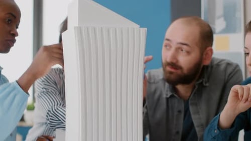 Close Up of Colleagues Pointing at Building Model and Maquette on Table