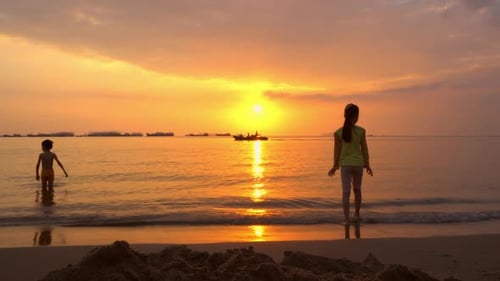 Silhouetten von Kindern, die in den Wellen des Ozeans spielen