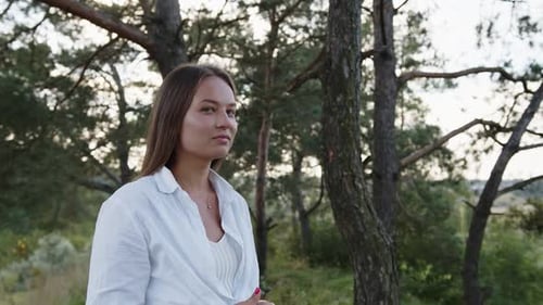 Woman Standing Outdoors Near Trees in a Forest