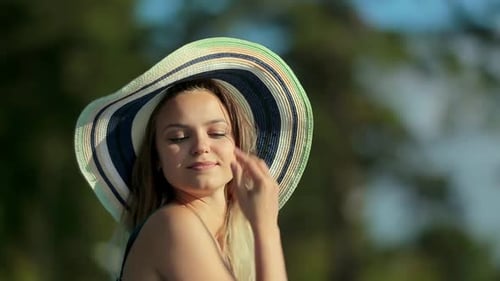 Woman in Striped Hat Smiling in Tropical Setting