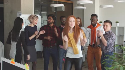 Un
manager rousse dans une tenue élégante divertit ses collègues. Danser au travail