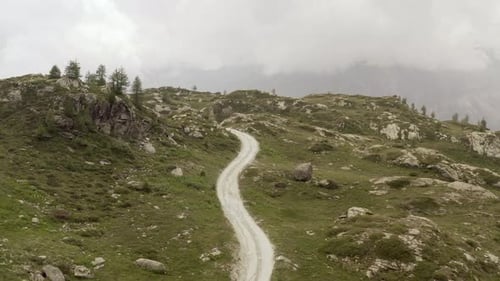 Cinematic Aerial View Gravel Trail Road on the Mountain. Cloudy Weater, Mist and Haze. Forward Dolly