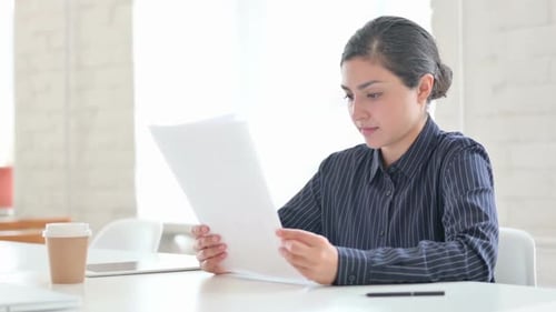 Woman Reviews Documents in a Bright Office