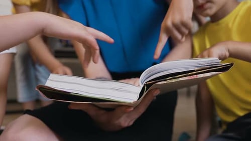 Kaukasische Kindergärtnerin und ihre Schüler sitzen auf Kissen