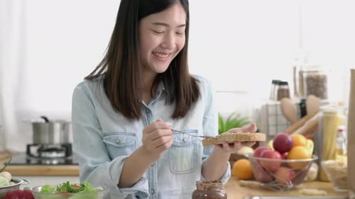 Woman Spreads Chocolate on Bread in Kitchen