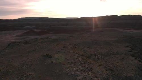 Volando hacia la puesta de sol sobre un terreno rocoso del desierto en Marte