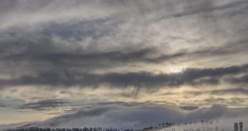 Zeitraffer der abendlichen Sonnenstrahlen, die durch die kalten nebligen Wolken in den Bergen auftauchen. Sonnenuntergang in