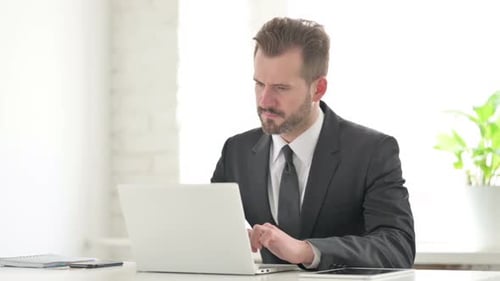 Young Businessman Having Neck Pain While Using Laptop in Office
