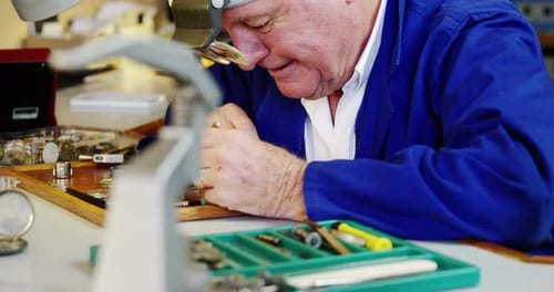 Gray-Haired Watchmaker Working at His Workbench