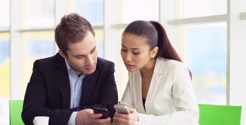 Business Professionals Using Smartphones at Table in Office