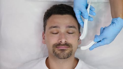 Man Receiving Facial Procedure From Aesthetician