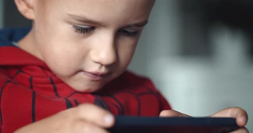 Boy Focused on Mobile Game Indoors