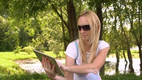 Young Woman Sitting in Park with Tablet Computer, Slow Motion.