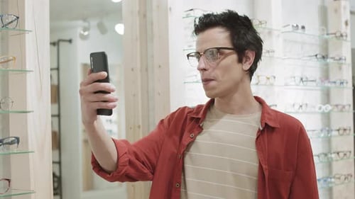 Young Man Trying on Sunglasses and Making Selfie
