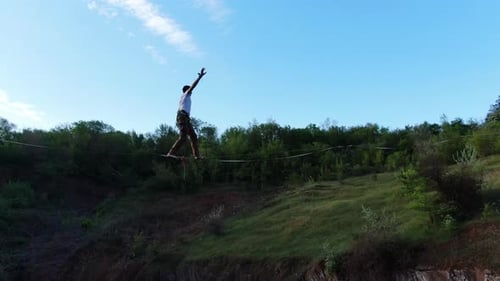 Man Tightrope Walking Over Canyon Falls