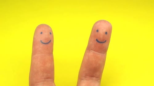 Menschliche Finger mit lächelnden Gesichtern zerreißen gelbes Papier