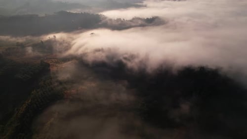 4K aerial view over mountain at sunrise in heavy fog. golden morning sunlight