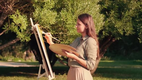 Woman Artist Paints a Picture on Canvas While Standing in a Park in Sunny Weather