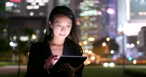 Woman Uses Tablet in City Park at Night
