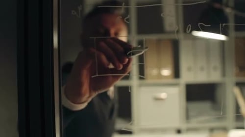 Man Drawing Business Charts on Glass Board