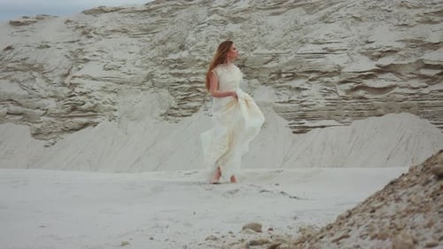 Elegant Woman Dancing in Desert Wearing White Dress