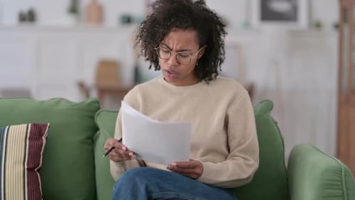 Woman Reviews Documents on Sofa at Home