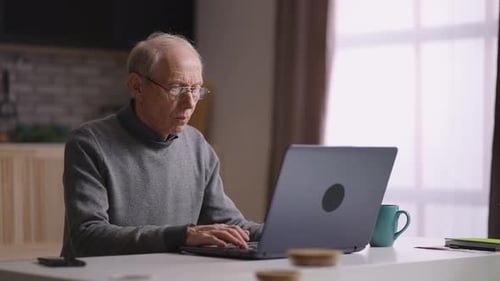 Senior Man Typing on Laptop at Home